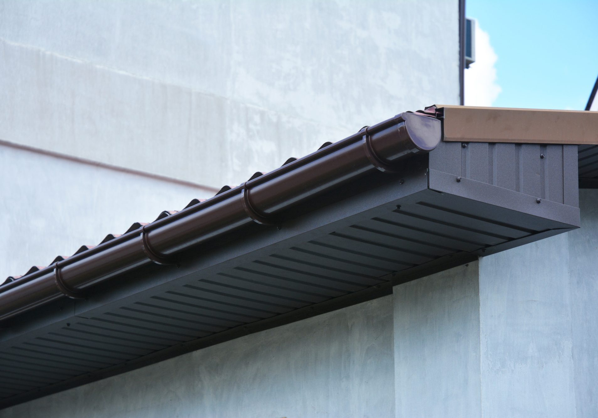 Close up on house plastic roof gutter with soffit and fascia board.