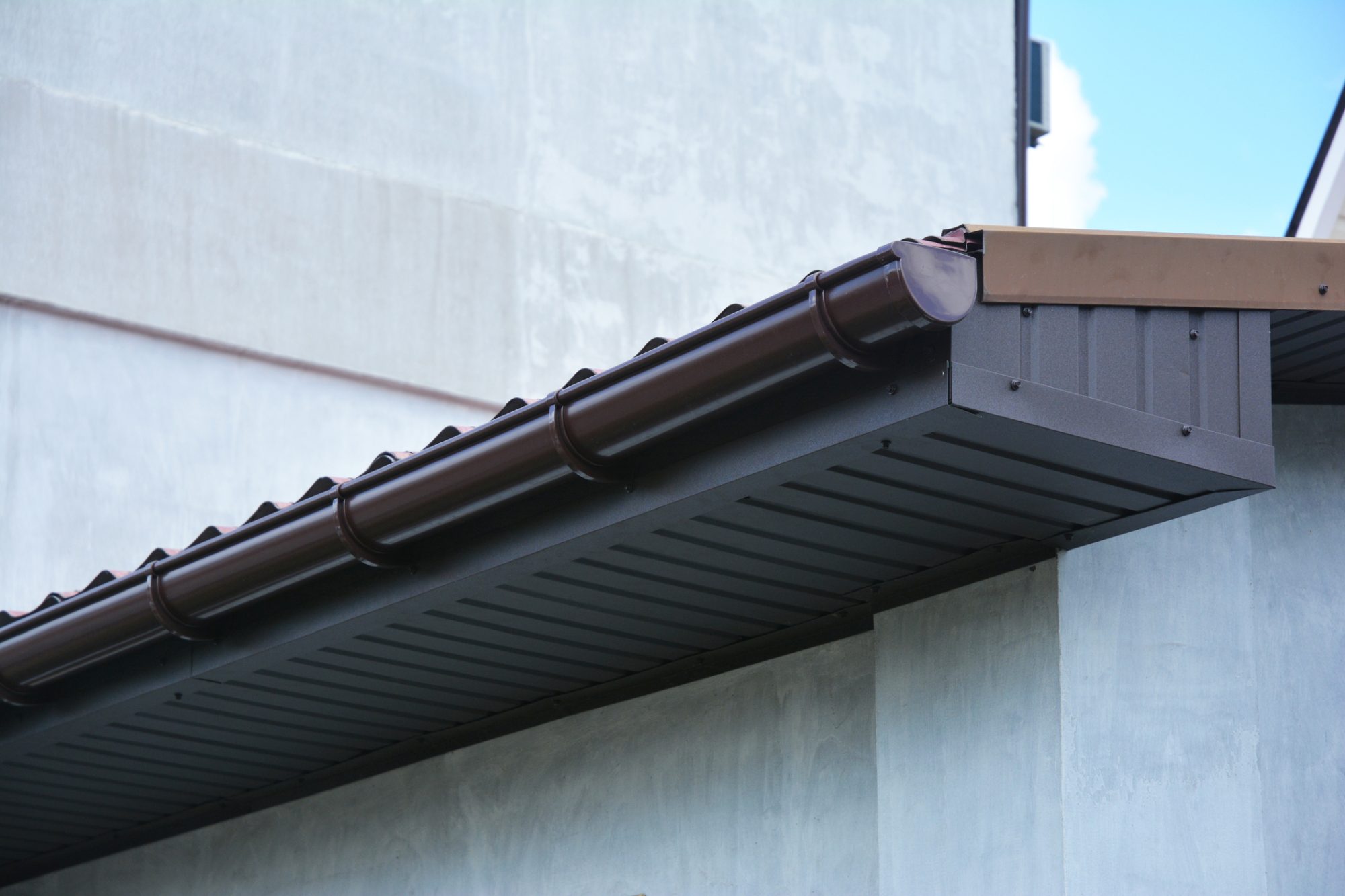 Close up on house plastic roof gutter with soffit and fascia board.
